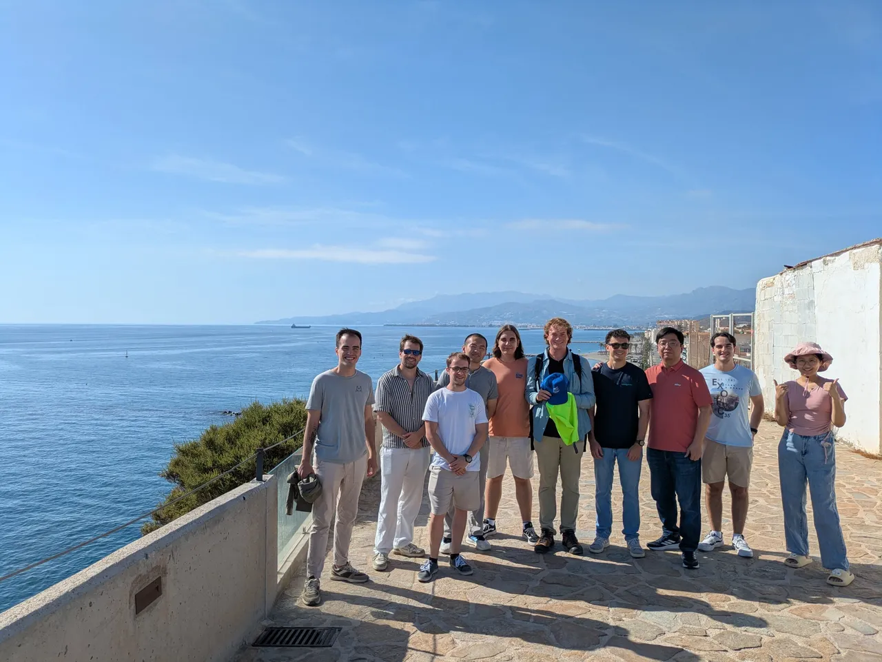 Martin Zoula, in the middle holding something yellow, standing with members of the lab on a seafront terrace